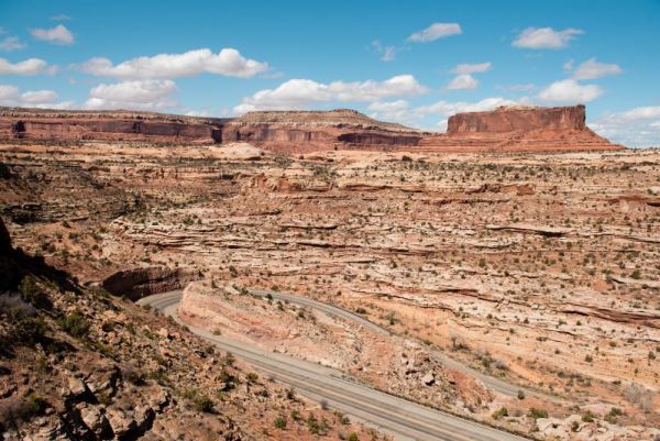 road curving around rocks near Moab Utah with mesas in background