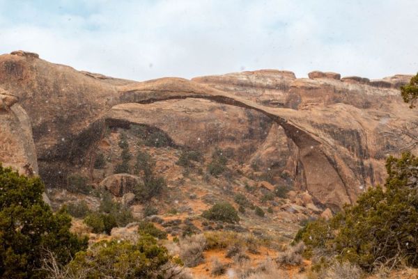 landscape arch with snow falling in arches national park