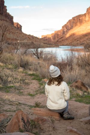 girl in white jacket and hat at campsite near Colorado River in Moab, Utah