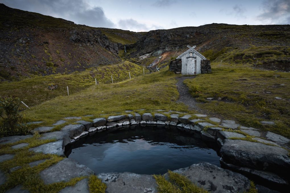 Guðrúnarlaug Hot Spring with small hut in the background in iceland on the ring road