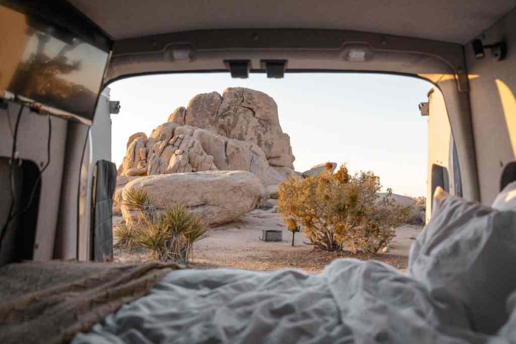 view out of bed of campervan in joshua tree national park looking at rocks