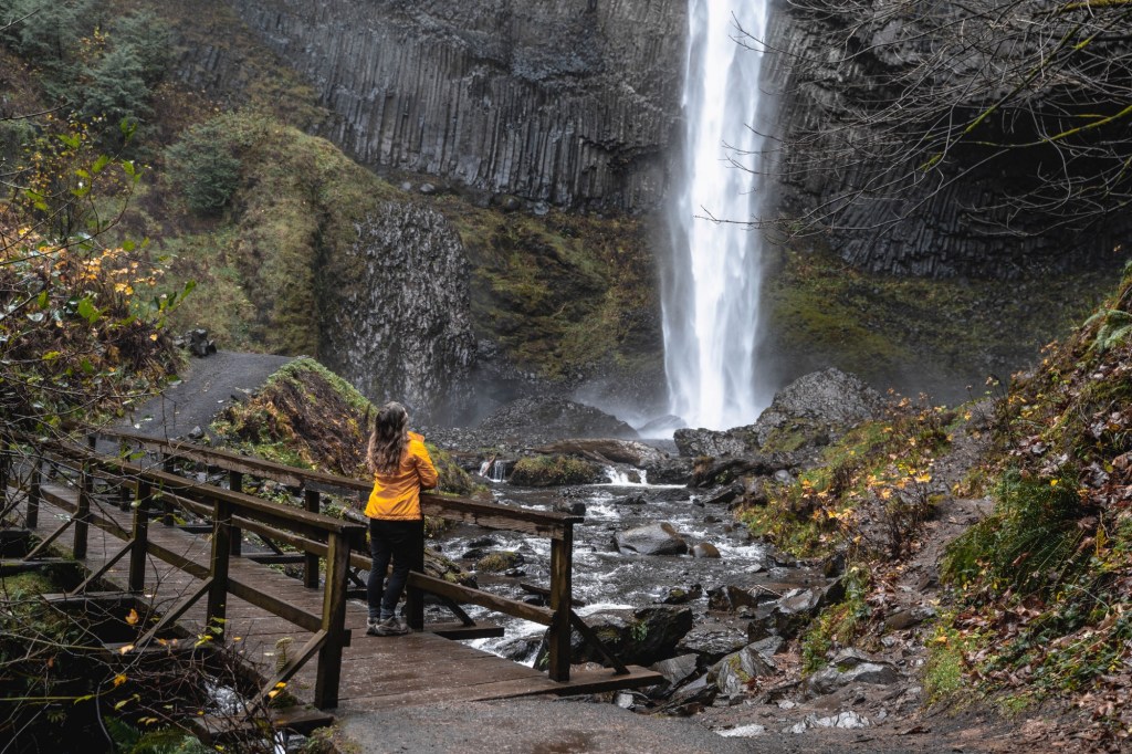 girl in yellow jacket looking at Latourell Falls on Latourell Falls Hike