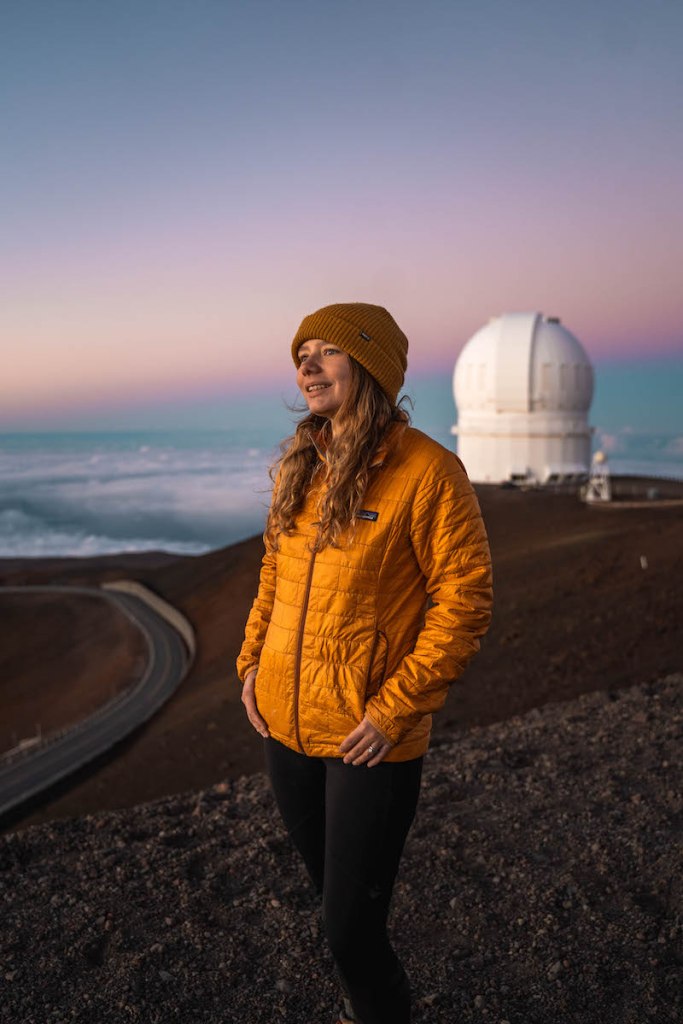 girl in yellow jacket and yellow hat watching the sun set from the summit of Mauna Kea on the Big Island of Hawaii