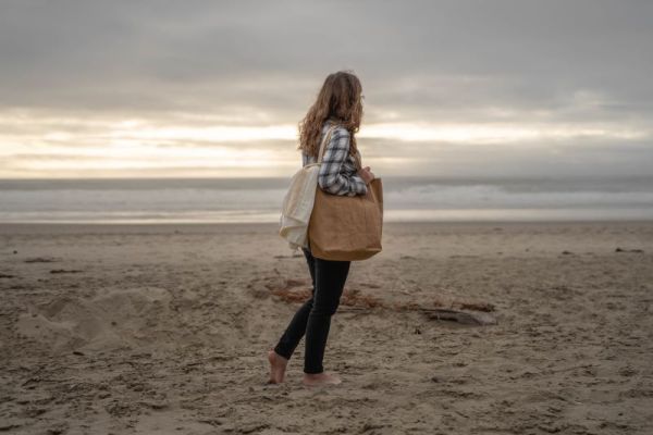 girl holding beach towel and tote on Oregon Coast