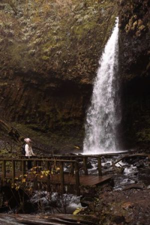 girl in pink hat looking at Upper Latourell Falls from the bridge