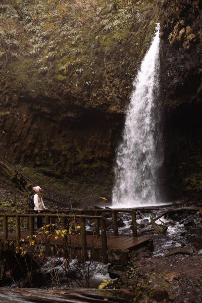 girl in pink hat looking at Upper Latourell Falls from the bridge