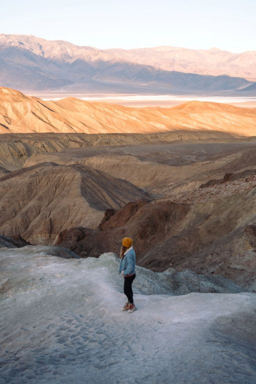 girl in jean jacket and yellow cap looking out at death valley from artist palette 