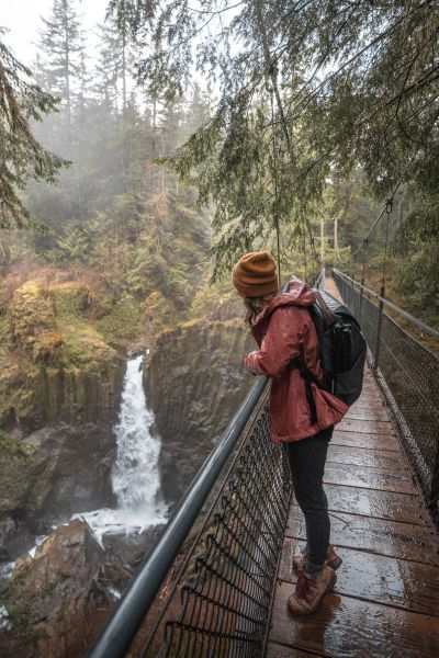 girl on suspension bridge looking at waterfall in Oregon