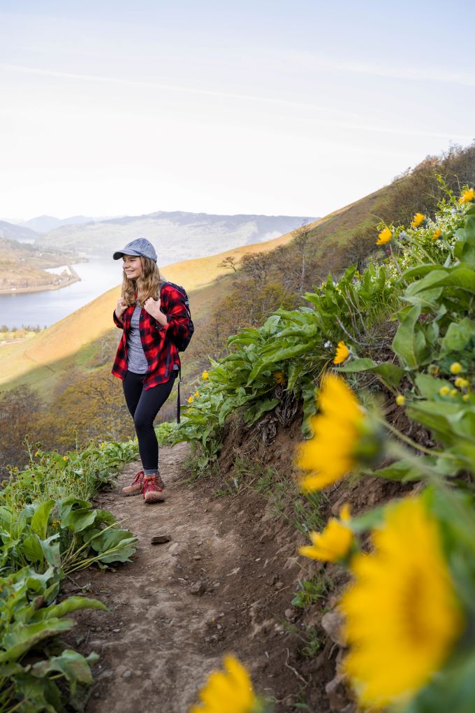 girl in flannel hiking with yellow wildflowers