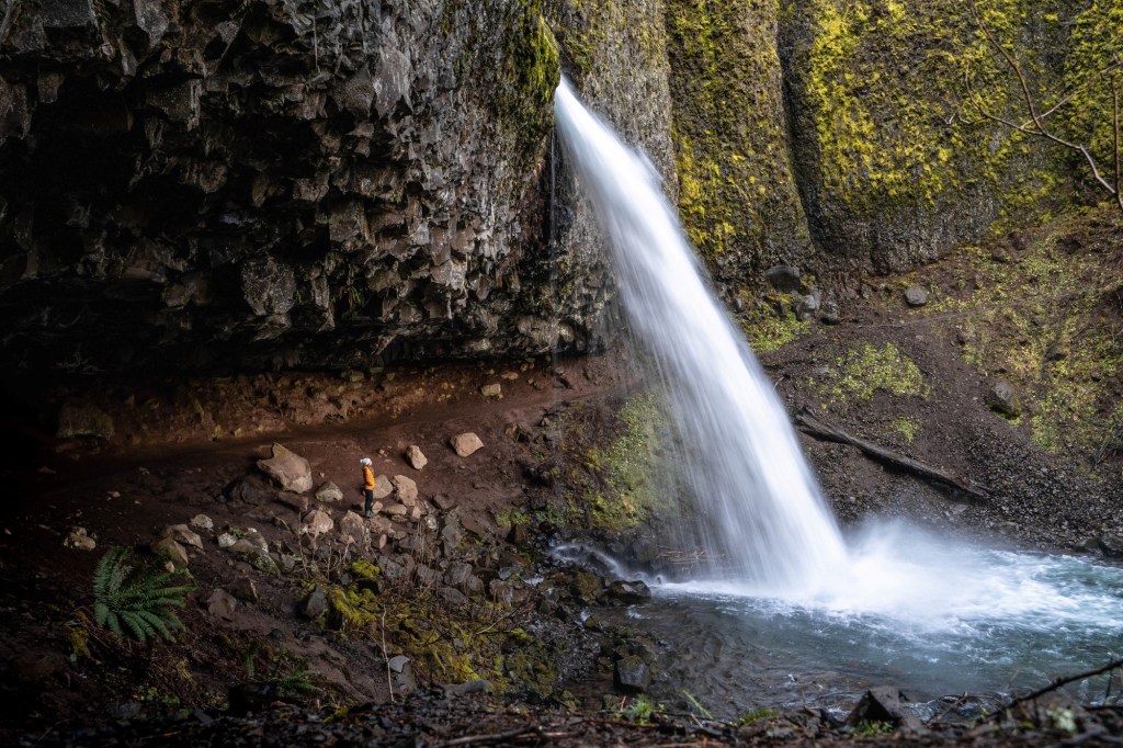 girl hiking behind waterfall in the gorge